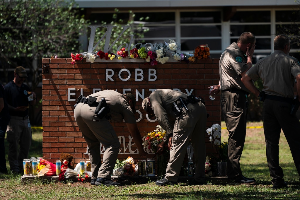 (Jae C. Hong | AP) Two Texas Troopers light a candle at Robb Elementary School in Uvalde, Texas, Wednesday, May 25, 2022, after a mass shooting.