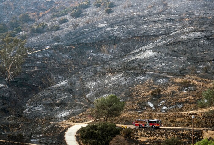 A fire engine drives past a burned area from a wildfire Monday, Sept. 4, 2017, in the Sunland-Tujunga section of Los Angeles. (AP Photo/Ringo H.W. Chiu)