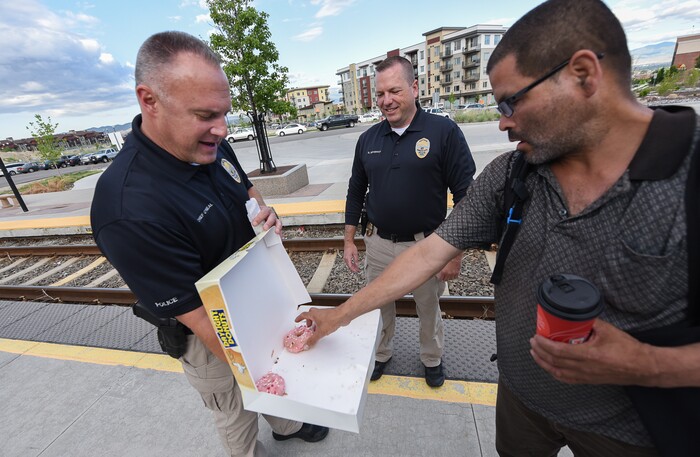(Francisco Kjolseth | The Salt Lake Tribune) Interim Sandy Police Chief Bill O'Neal, left, is joined by Captain Greg Severson as they hand out a donuts to morning commuters including Dave Chavez in honor of National Donut Day on Friday, June 1, 2018, at the Sandy Civic Center TRAX Station.