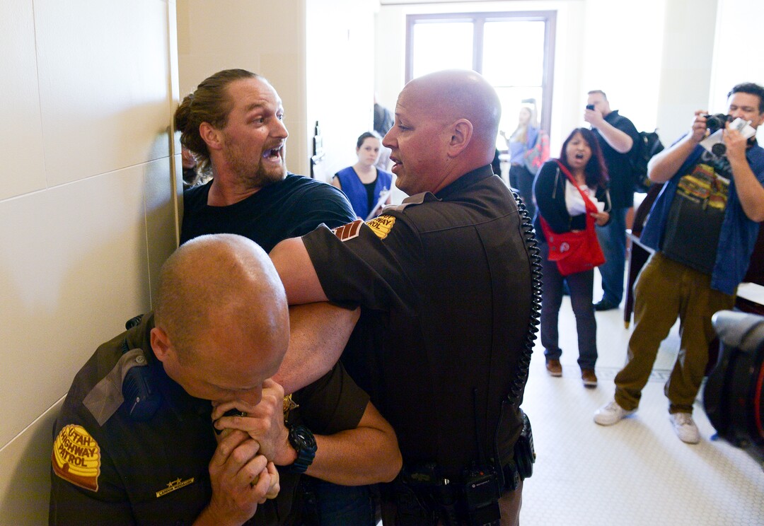 (Leah Hogsten  |  The Salt Lake Tribune) Ethan PetersenÊwithÊCivil Riot, a SLC-basedÊcivilÊresistance collective, and other opponents of the proposed inland port are escorted out of the Utah Inland Port Authority Board meeting by Utah Highway Patrol officers at the Capitol, June 5, 2019. The Inland Port Authority Board had to cancel its meeting last month after a group of protesters took over the meeting. Petersen was arrested.