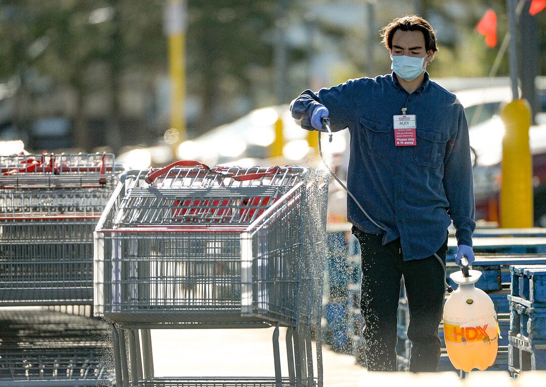 (Francisco Kjolseth  |  The Salt Lake Tribune) Costco staff sanitize shopping carts as they begin implementing a policy on Monday, May 4, 2020, that everyone in the store, including shoppers, have to wear a mask.
