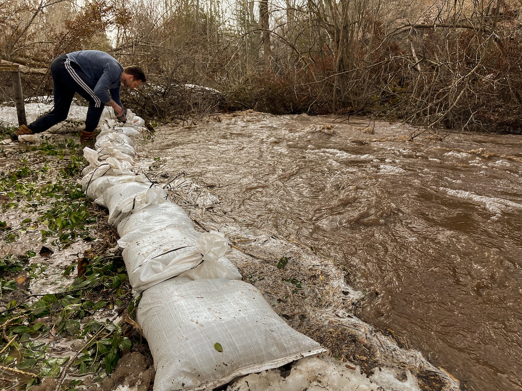 (Trent Nelson  |  The Salt Lake Tribune) Alex Klivecka puts down sandbags as Emigration Creek rises in Emigration Canyon on Wednesday, April 12, 2023. Emigration Creek is under flood advisory again.