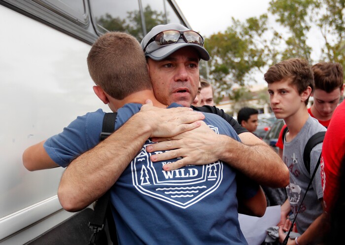 Tom Carmo, father of survivor Ethan Rocha, hugs student Joey Cordova, as students from Stoneman Douglas High School board buses in Parkland, Fla., Tuesday, Feb. 20, 2018. The students plan to hold a rally Wednesday in hopes that it will put pressure on the state's Republican-controlled Legislature to consider a sweeping package of gun-control laws, something some GOP lawmakers said Monday they would consider.  (AP Photo/Gerald Herbert)