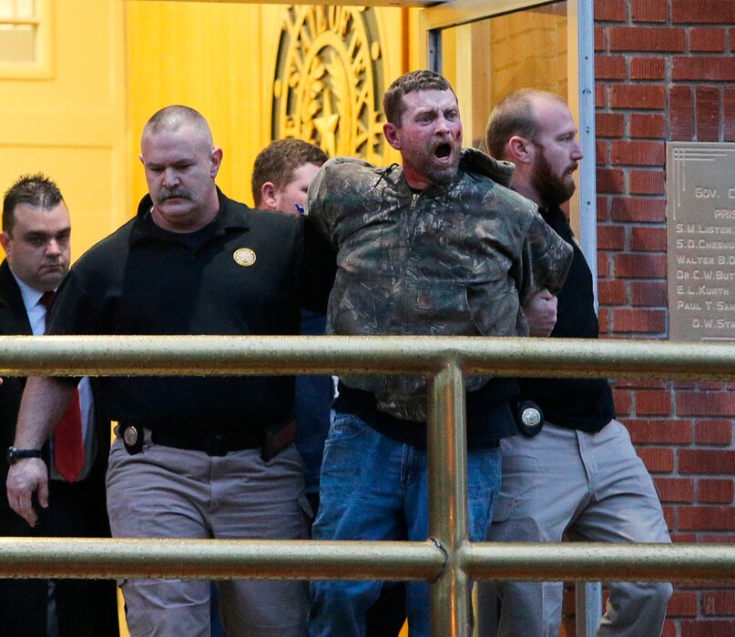 (Jerry Larson/Waco Tribune-Herald via AP) In this Thursday, Feb. 28, 2019 photo, Gordon Coble, center, is led out of the of the Texas State Penitentiary in Huntsville, Texas, after reacting to the execution of his father, Billie Wayne Coble.  Chaos erupted outside Texas' death chamber Thursday night when the son of the condemned inmate pounded on the chamber windows, shouted obscenities and threw fists after his father spoke his final words.