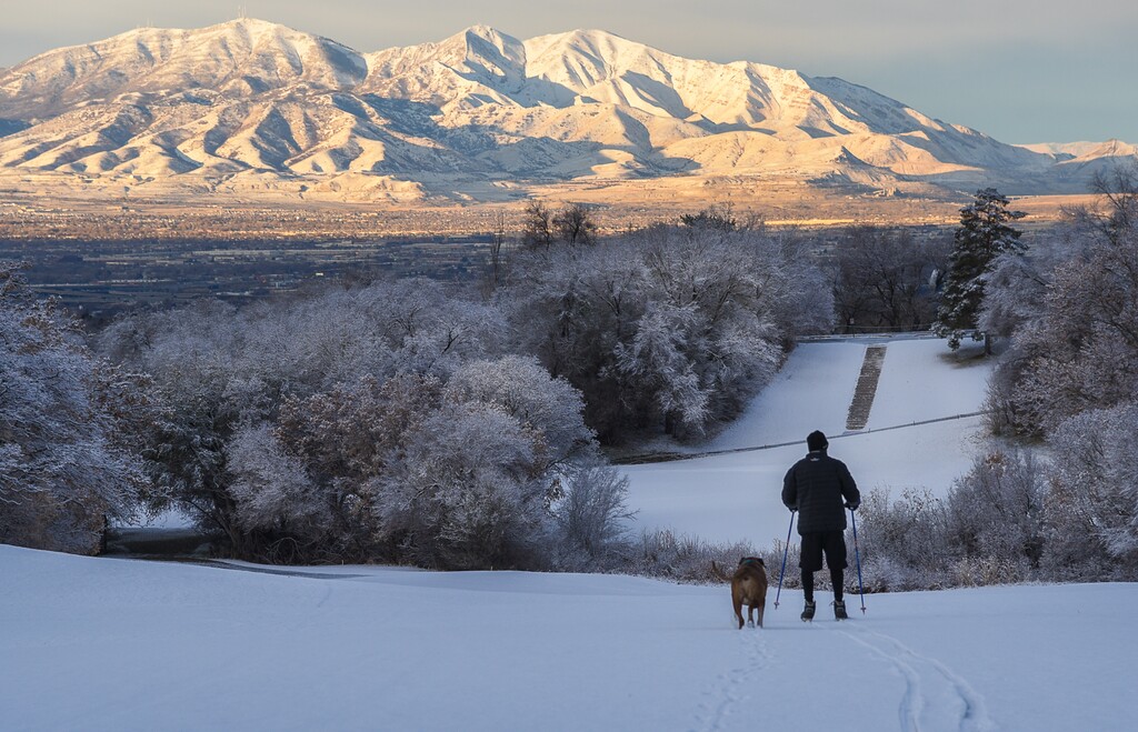 (Francisco Kjolseth | The Salt Lake Tribune) The Oquirrh Mountains are lit up by the early morning sun as recently retired Dr. Rick Anderson makes sure his dog Buddy gets a little exercise at on the slopes of Bonneville Golf Course on Saturday, Dec. 1, 2018. "My job is now skiing," said Anderson with plans to head to Alta for some fresh tracks on his own.