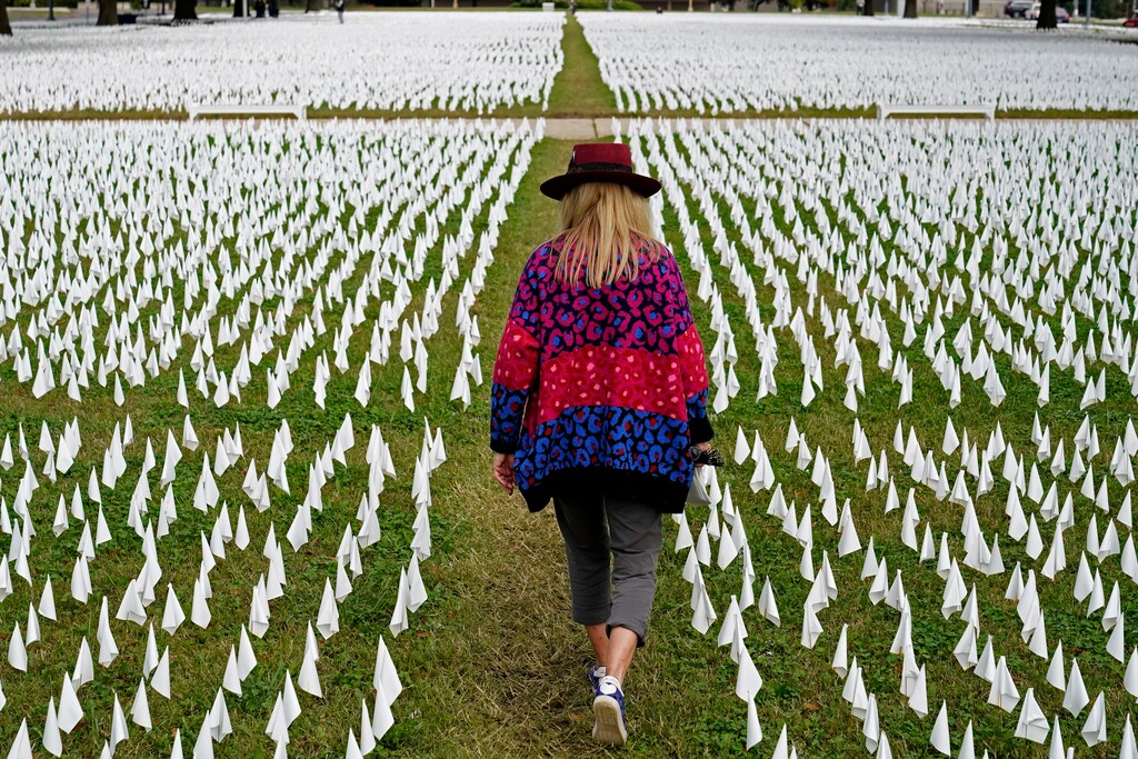 (Patrick Semansky, AP file photo) In this Oct. 27, 2020, photo artist Suzanne Brennan Firstenberg walks among thousands of white flags planted in remembrance of Americans who have died of COVID-19 near Robert F. Kennedy Memorial Stadium in Washington.