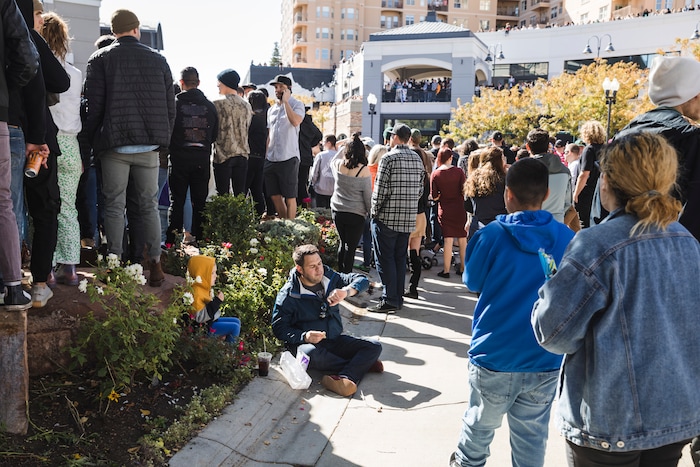 (Clark Clifford  |  Special to The Salt Lake Tribune) A man sits in the gutter next to his son while he waits for the start of Kanye West's Sunday Service at The Gateway in Salt Lake City on Saturday, Oct. 5, 2019.