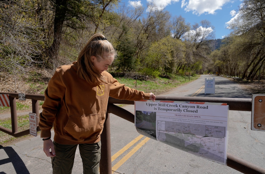 (Francisco Kjolseth  | The Salt Lake Tribune) Darcy Lytle, a recreation technician with the U.S. Forest Service attaches a road closure sign at the winter gate in Mill Creek Canyon on Tuesday, April 29, 2025. Starting Thursday, the road beyond the winter gate is slated to be closed for nearly two years in Phase 1 of a project to shore up the road, create a bike lane and add new parking lots.