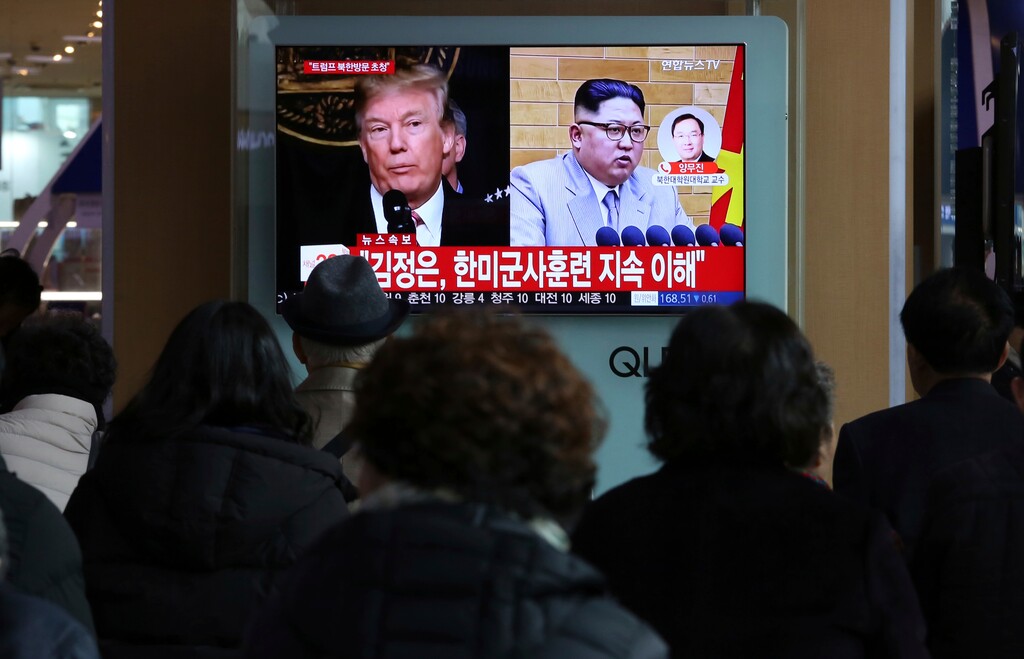 People watch a TV screen showing North Korean leader Kim Jong Un and U.S. President Donald Trump, left, at the Seoul Railway Station in Seoul, South Korea, Friday, March 9, 2018. After months of trading insults and threats of nuclear annihilation, Trump agreed to meet with Kim by the end of May to negotiate an end to Pyongyang's nuclear weapons program, South Korean and U.S. officials said Thursday. No sitting American president has ever met with a North Korea leader. The signs read: " Kim Jong Un understands that the routine joint military exercises between the South Korean and the United States must continue." (AP Photo/Ahn Young-joon)