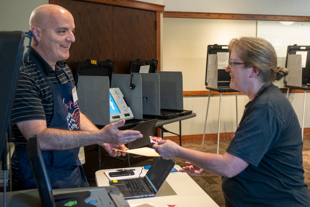 (Rick Egan | The Salt Lake Tribune) Poll Manager Luke Todd  hands an "I voted" sticker to Sherri Stringham at the Centerville Library, on Tuesday, June 23, 2026.