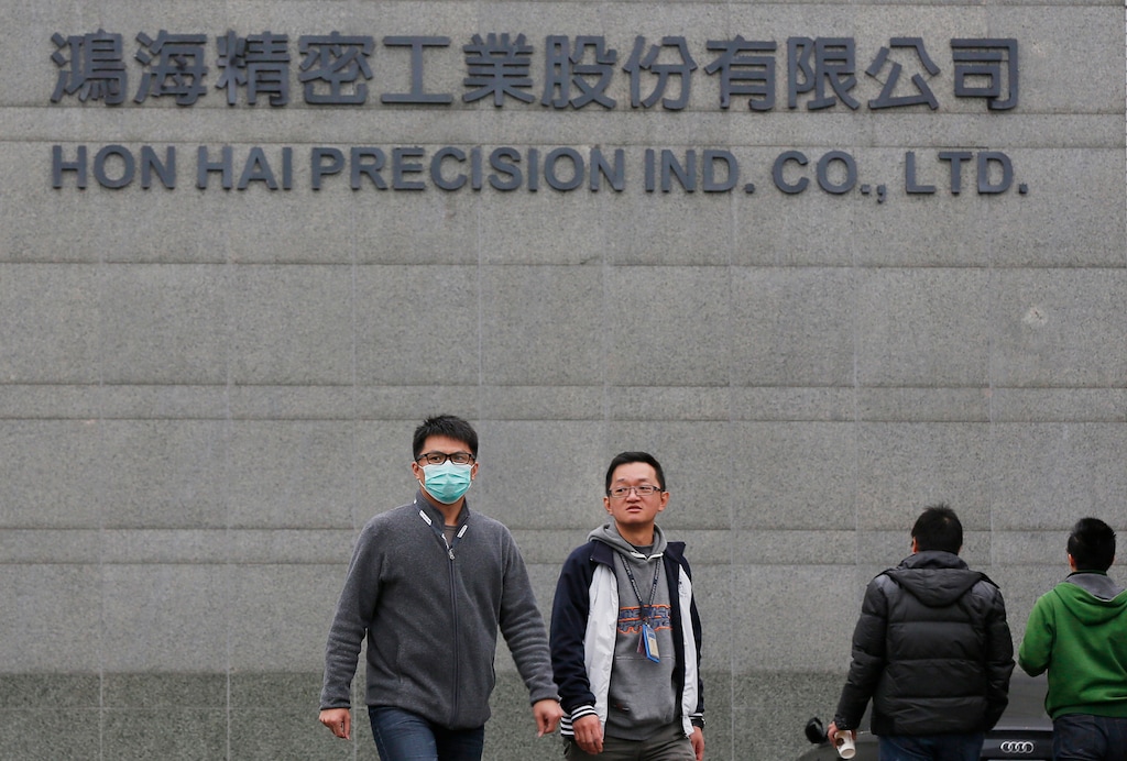FILE - In this Feb. 4, 2016, file photo, employees enter and exit the headquarters of Taiwan's Hon Hai Precision Industry Co., also known as Foxconn, in New Taipei City, Taiwan. Gov. Scott Walker says President Donald Trump plans to make a "major jobs announcement for Wisconsin" as anticipation builds it will be about electronics giant Foxconn locating in the state. Taiwan-based Foxconn is best known as the assembler of the iPhone. Wisconsin is among seven states, mostly in the Midwest, that the company has named as possible locations to build the its first liquid-crystal display factory that could mean tens of thousands of jobs. (AP Photo/Wally Santana, File)