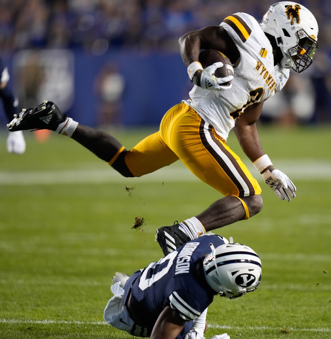 (Francisco Kjolseth | The Salt Lake Tribune) Wyoming Cowboys running back Titus Swen (2) steps over Brigham Young Cougars defensive back Jakob Robinson (0) in football action between the Brigham Young Cougars and the Wyoming Cowboys at LaVell Edwards Stadium in Provo, on Saturday, Sept. 24, 2022.