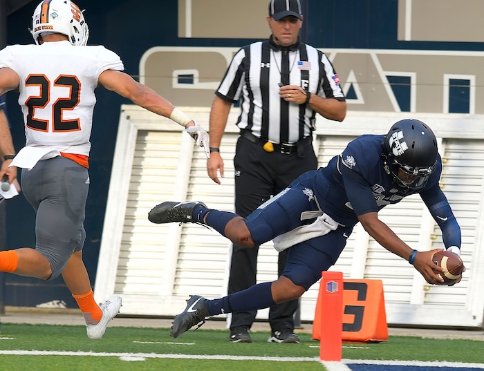 Utah State quarterback Kent Myers (2) dives into the end zone for a touchdown as Idaho State defensive back Nikko Hayes (22) watches during an NCAA college football game Thursday, Sept. 7, 2017, in Logan, Utah. (Eli Lucero/Herald Journal via AP)