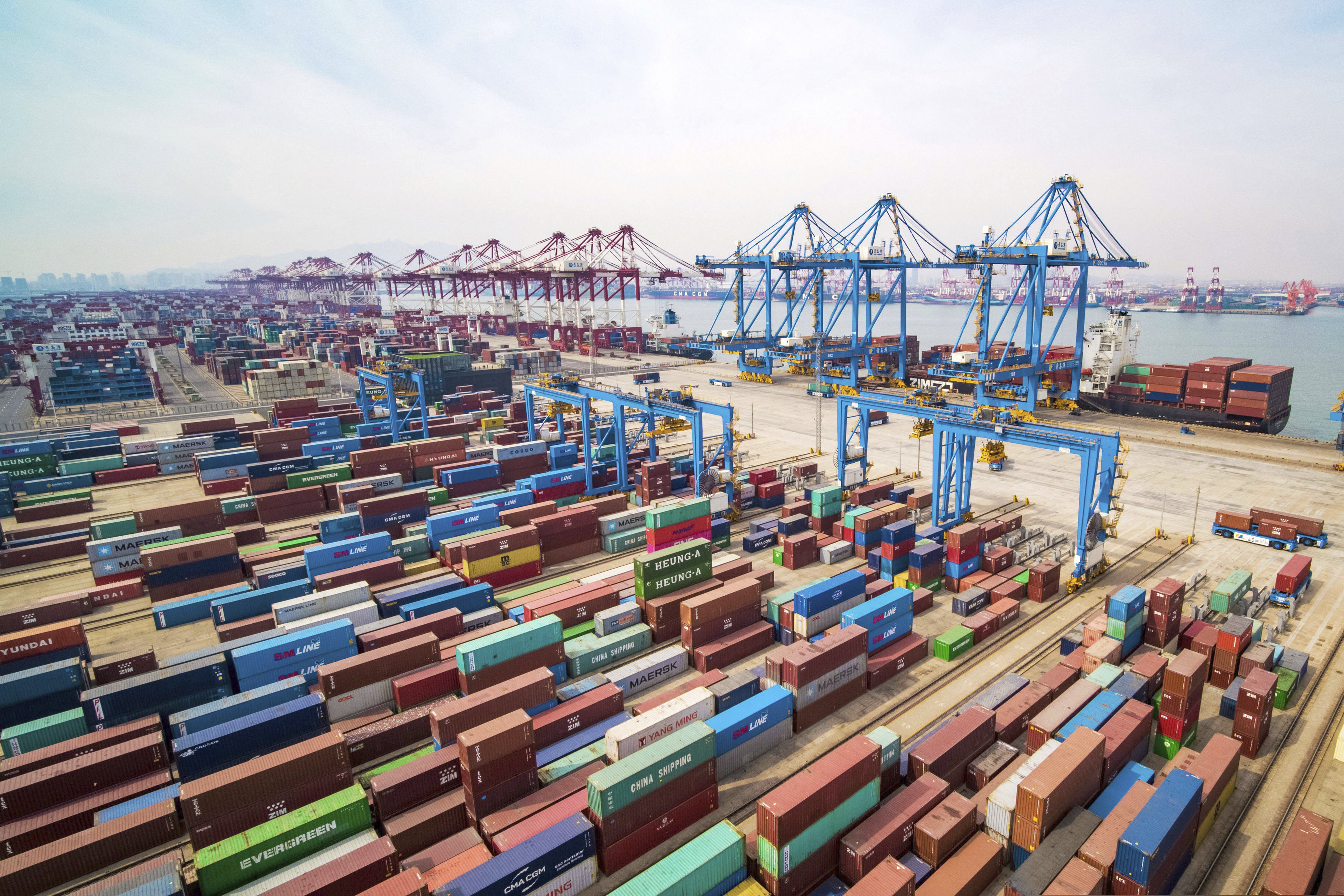 (Chinatopix file photo via AP) In this March 8, 2019, file photo, trucks move at a container port in Qingdao in eastern China's Shandong Province. China’s economic growth held steady in the latest quarter amid a tariff war with Washington.