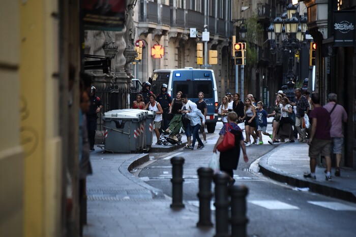 (Giannis Papanikos | The Associated Press) People flee the scene in Barcelona, Spain, Thursday, Aug. 17, 2017, as police officers patrols after a white van jumped the sidewalk in the historic Las Ramblas district, crashing into a summer crowd of residents and tourists and injuring several people, police said.