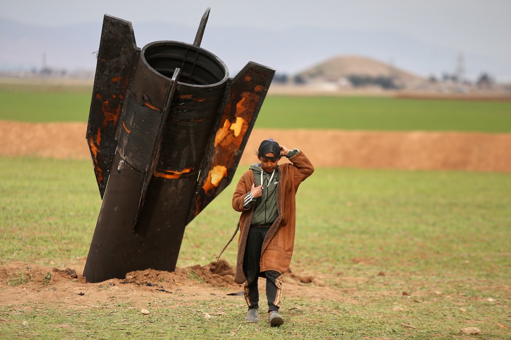 (Baderkhan Ahmad | AP) A shepherd boy walks away from an unexploded Iranian projectile that landed in an open field in the outskirts of Qamishli, eastern Syria.