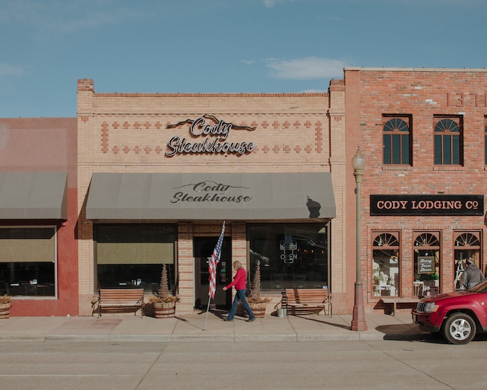 (Elliot Ross | The New York Times) A woman walks past the Cody Steakhouse on Sheridan Avenue in downtown Cody, Wyo., Jan. 28, 2020. Kanye West hangs out at the restaurant on the main drag, which is also where he met one of his intern videographers, a student at Cody High.