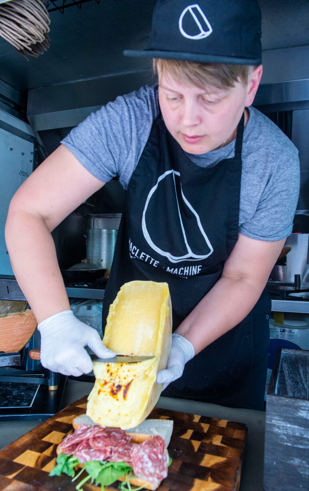 (Rick Egan  |  The Salt Lake Tribune)   Abby Pfunder slides off the melted cheese as she makes "The Alpine" in the Raclette Machine food truck, Wednesday, June 26, 2019. The food truck will be part of the Food Truck and Brewery Battle at The Gateway on Aug. 3.