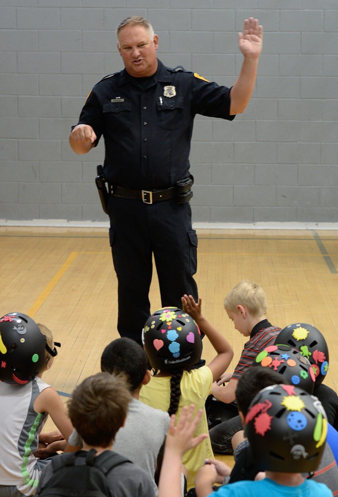 (Francisco Kjolseth  |  The Salt Lake Tribune)  Detective Greg Wilking shows kids the proper way of signaling their turns while on the bike as more than 50 Salt Lake City-area kids received a new bicycle helmet at the Capitol West Boys & Girls Club on Tuesday, July 31, 2018. As part of UnitedHealthcare's Pro Cycling team and community outreach program to keep kids healthy and active, team cyclists Jonny Clarke and Sebastian Haedo engaged the kids in a few warm up routines before getting on the bike.