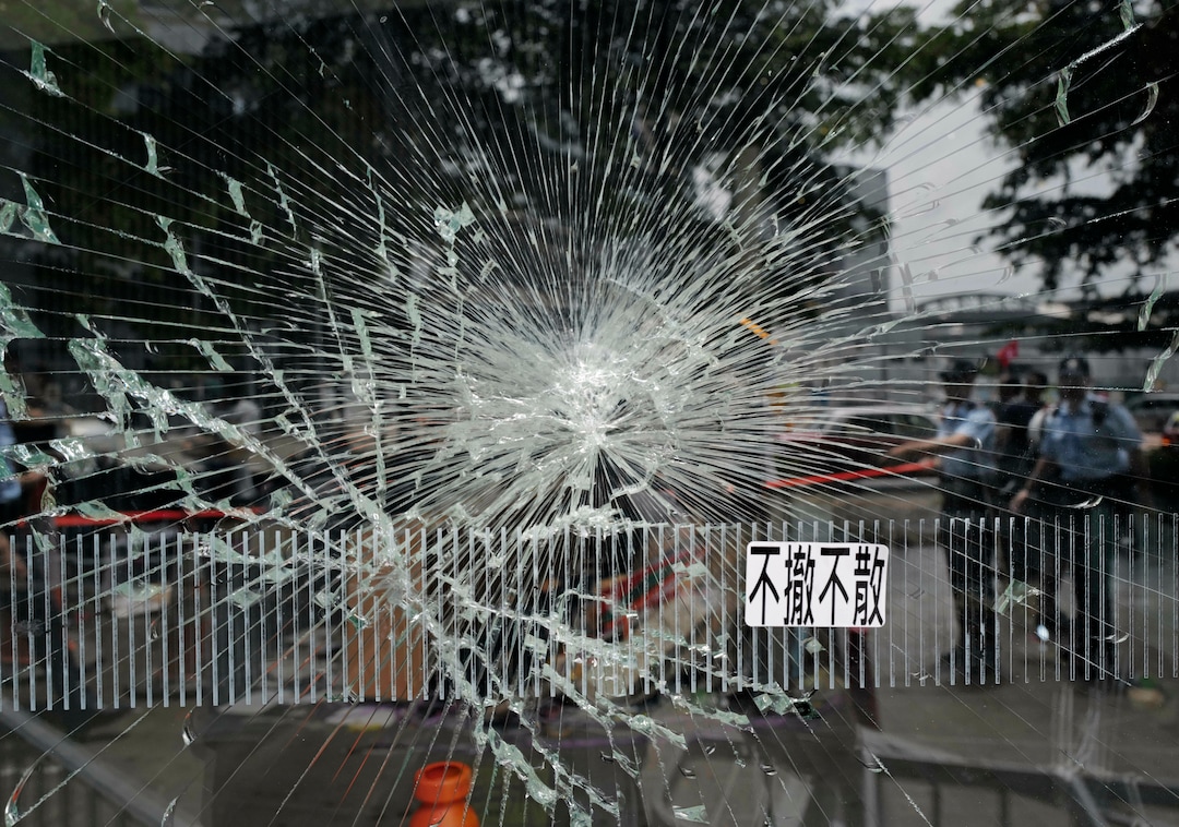 (Vincent Yu | AP Photo) Police officers stand guard near a broken glass outside Legislative Council building in Hong Kong, Tuesday, July 2, 2019. Hundreds of protesters swarmed into Hong Kong's legislature Monday night, defacing portraits of lawmakers and spray-painting pro-democracy slogans in the chamber before vacating it as riot police cleared surrounding streets with tear gas and then moved inside. The words read " not leave, not withdraw."