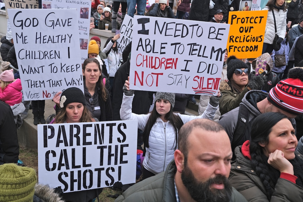 People hold signs during a protest at the state house in Trenton, N.J., Monday, Jan. 13, 2020. New Jersey lawmakers are set to vote Monday on legislation to eliminate most religious exemptions for vaccines for schoolchildren, as opponents crowd the statehouse grounds with flags and banners, including some reading "My Child, My Choice." (AP Photo/Seth Wenig)