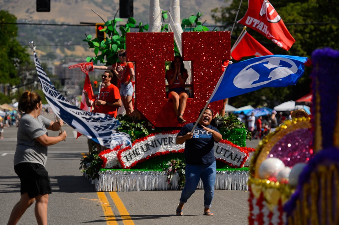 (Trent Nelson | The Salt Lake Tribune)  The Days of '47 Parade in Salt Lake City, Tuesday July 24, 2018. Two BYU fans rush out to wave their flags in front of the University of Utah's float.