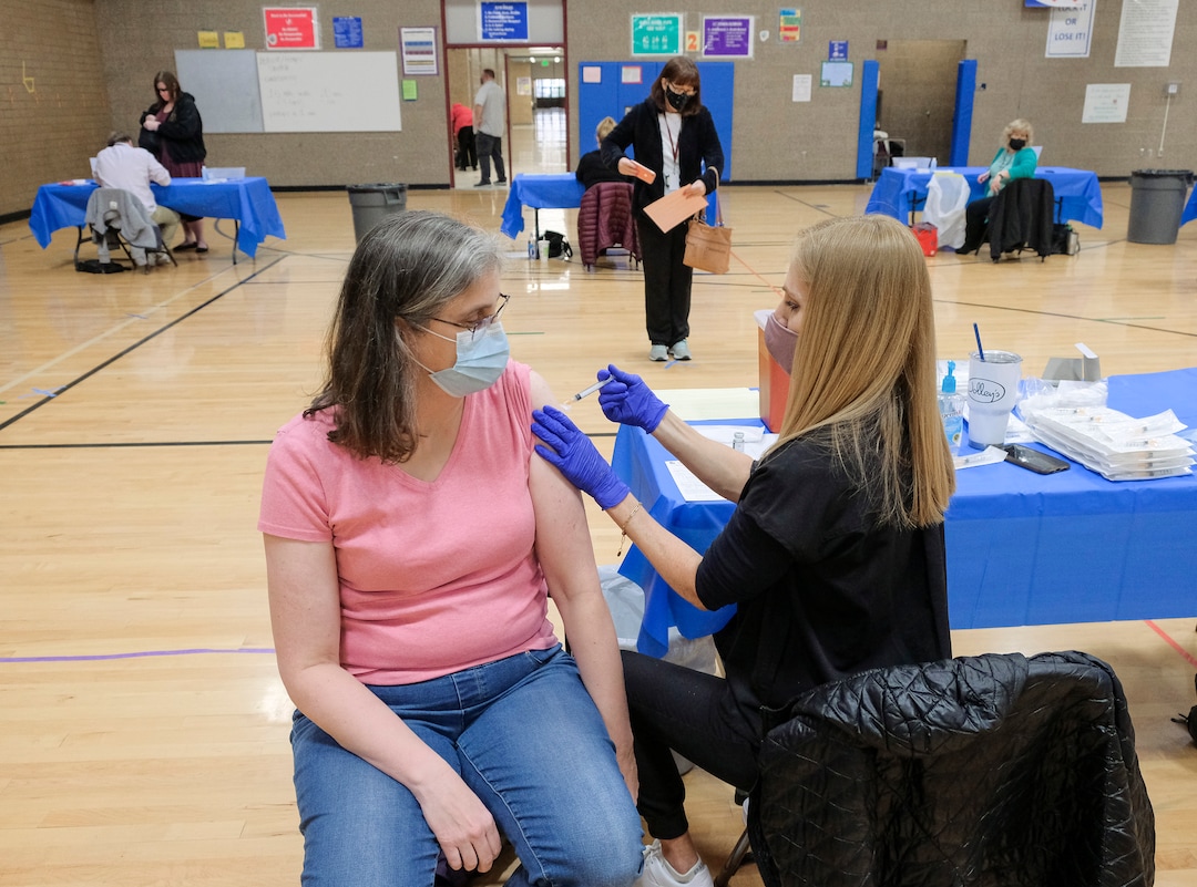 (Leah Hogsten | The Salt Lake Tribune) West Hills Middle School science teacher Stefani Arnesen recives her second covid-19 vaccination from nurse Angie Boren. Employees of the Jordan School District were invited to West Hills Middle School to receive their coronavirus vaccination, Feb. 12, 2021.