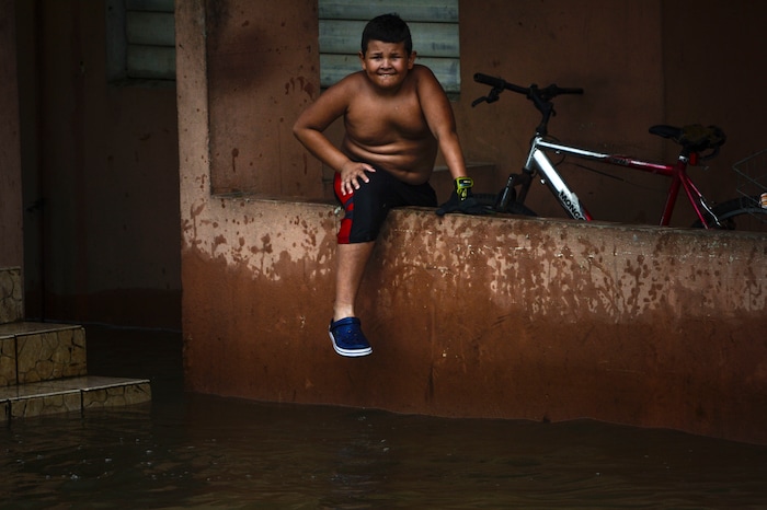 A boy sits by a flooded area at the Ingenio community after the passing of Hurricane Maria, in Puerto Rico, Friday, September 22, 2017. Because of the heavy rains brought by Maria, thousands of people were evacuated from Toa Baja after the municipal government opened the gates of the Rio La Plata Dam. (AP Photo/Carlos Giusti)