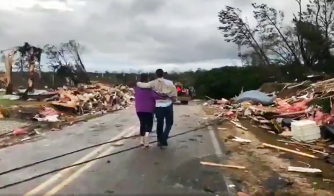 (WKRG-TV via AP)  People walk amid debris in Lee County, Ala., after what appeared to be a tornado struck in the area Sunday, March 3, 2019. Severe storms destroyed mobile homes, snapped trees and left a trail of destruction amid weather warnings extending into Georgia, Florida and South Carolina, authorities said.