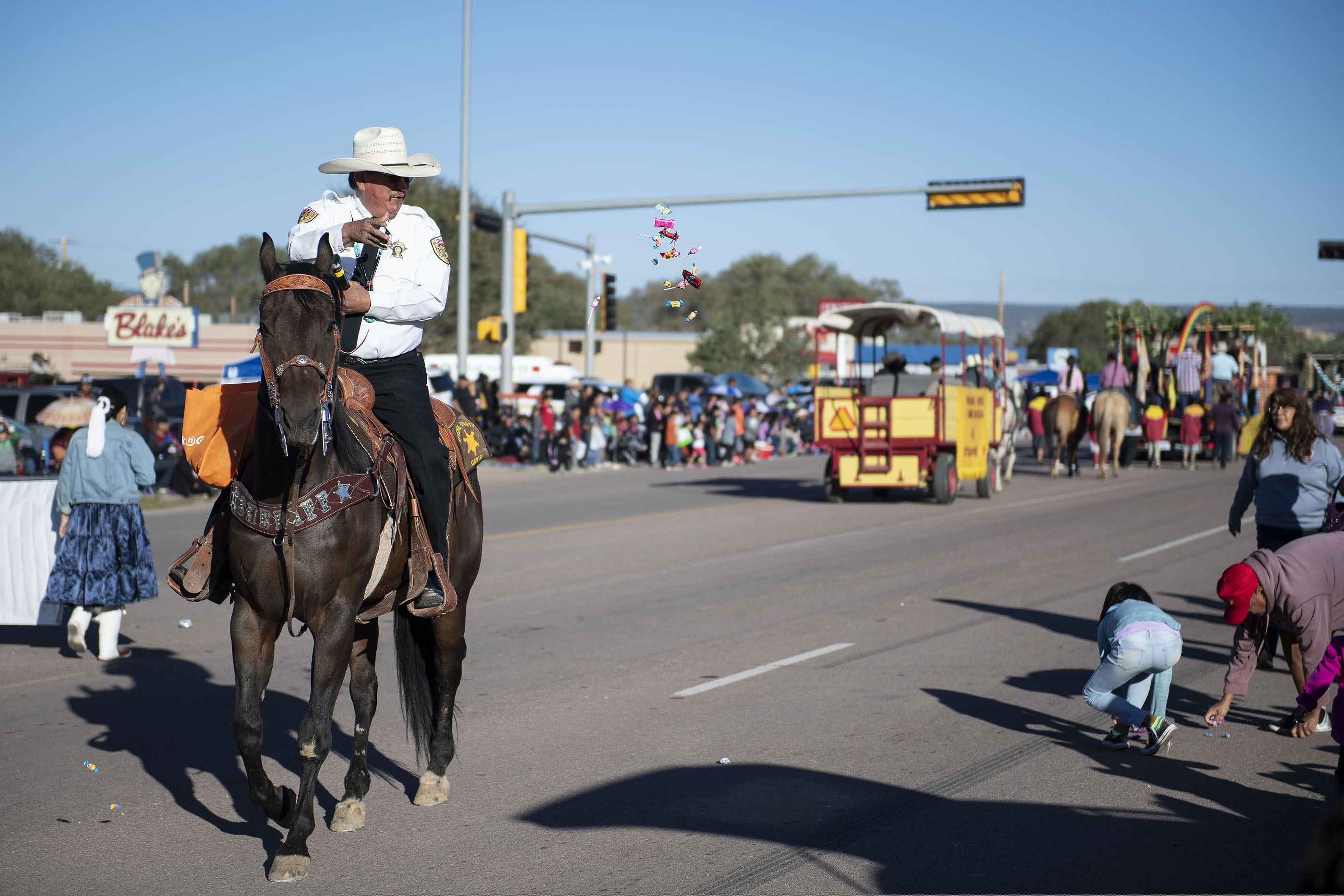 (Alma E. Hernandez | Gallup Independent via AP) In this Sept. 8, 2018 image, Sheriff Joseph Dedman, Jr. throws candy at the crowd during the Navajo Nation Fair Parade near Tse Bonito, New Mexico.