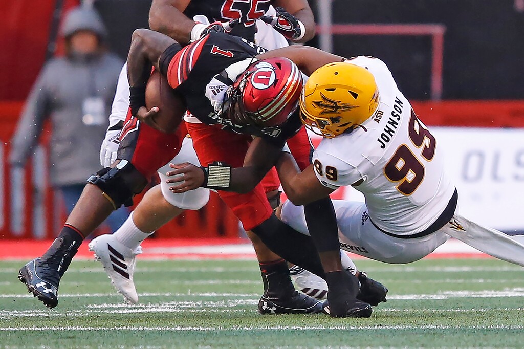 (Rick Bowmer | AP) Utah quarterback Tyler Huntley (1) escapes a tackle attempt by Arizona State defensive lineman Amiri Johnson (99) during the first half of an NCAA college football game Saturday, Oct. 19, 2019, in Salt Lake City.