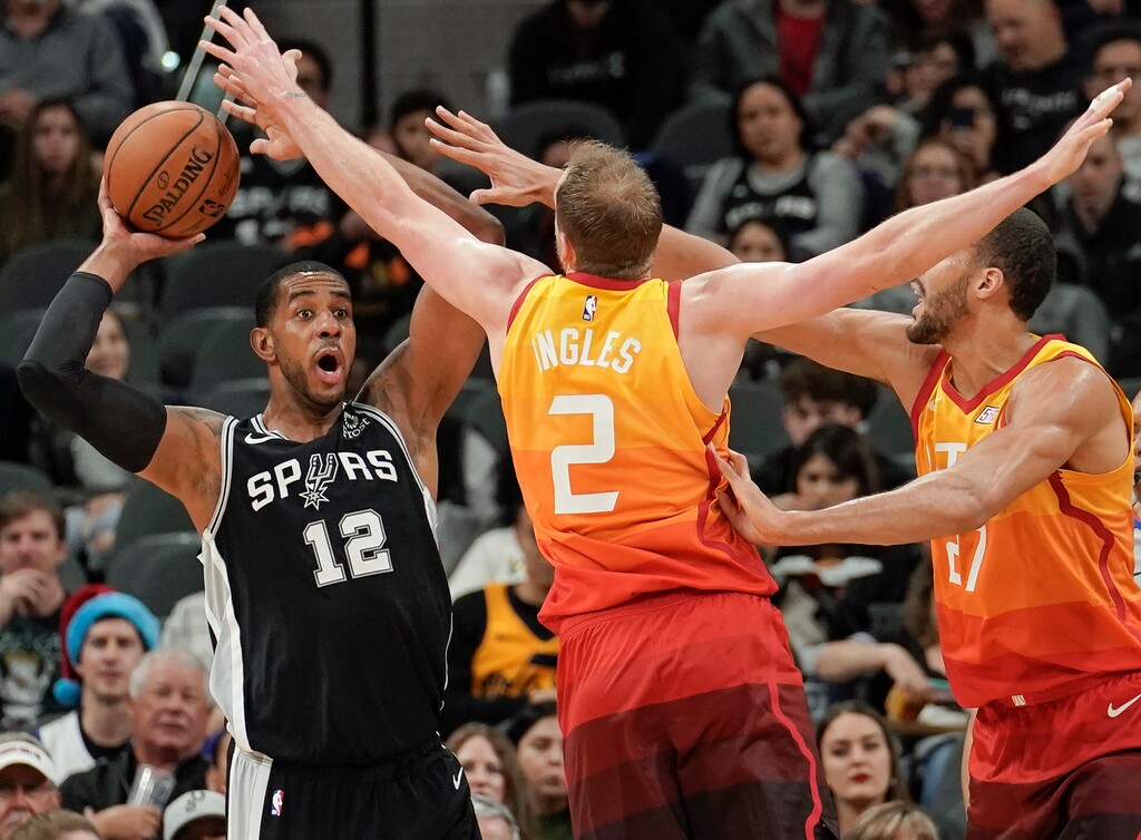 San Antonio Spurs forward LaMarcus Aldridge (12) looks to pass as he is defended by Utah Jazz forward Joe Ingles (2) and center Rudy Gobert during the first half of an NBA basketball game, Sunday, Dec. 9, 2018, in San Antonio. San Antonio won 110-97. (AP Photo/Darren Abate)