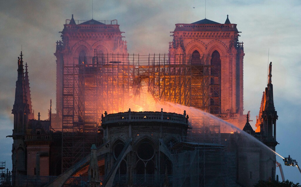 Photo by Raphael Lafargue/Abaca/Sipa USA(Sipa via AP Images) Bystanders look on as flames and smoke are seen billowing from the roof at Notre-Dame Cathedral with river in Paris on April 15, 2019. A fire broke out at the landmark Notre-Dame Cathedral in central Paris, potentially involving renovation works being carried out at the site, the fire service said.Images posted on social media showed flames and huge clouds of smoke billowing above the roof of the gothic cathedral, the most visited historic monument in Europe.