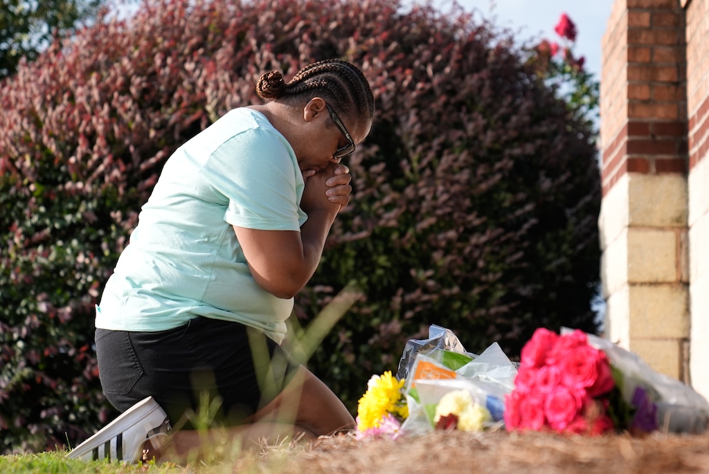 (Brynn Anderson | The Associated Press) Linda Carter, of Grayson, Ga., kneels near Apalachee High School to place flowers as she mourns for the slain students and teachers on Thursday, Sept. 5, 2024, in Winder, Ga.