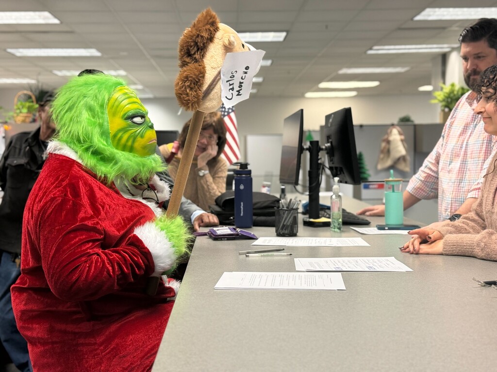 (Jordan Miller | The Salt Lake Tribune) A resident dressed in a Grinch costume at the Salt Lake County clerk's office signs the petition for a referendum over the county's property tax hike, Monday, Dec. 15, 2025.