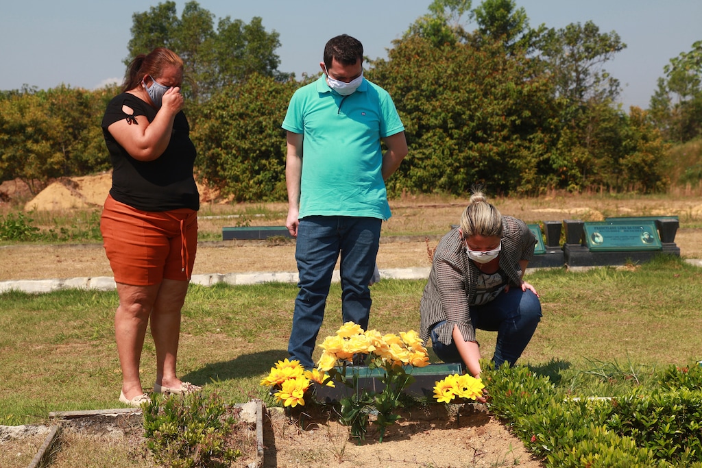 (Helton Belo | AP) Sisters Valeria Melo da Silva, left, and Viviane, her husband Luigi do Nascimento visit the grave of their mother who died of COVID-19, at a cemetery in Manaus, Brazil, Tuesday, Aug. 4, 2020. Their 67-year-old mother reported having a cold, and a few days later started having problems breathing. She died after five days in a public hospital. “I still don’t accept her death, not yet,” said Viviane, crying, and expressing regret the family had been unable to hold a wake for her mother.