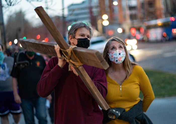 (Francisco Kjolseth | The Salt Lake Tribune) Maurice Mede and his wife Audrey takes a turn carrying the cross as mask wearing Utah Christians walk the streets of Salt Lake City beginning at Cathedral of the Madeleine on Good Friday, to symbolically mark Jesus' carrying the cross to his crucifixion, April 2, 2021.