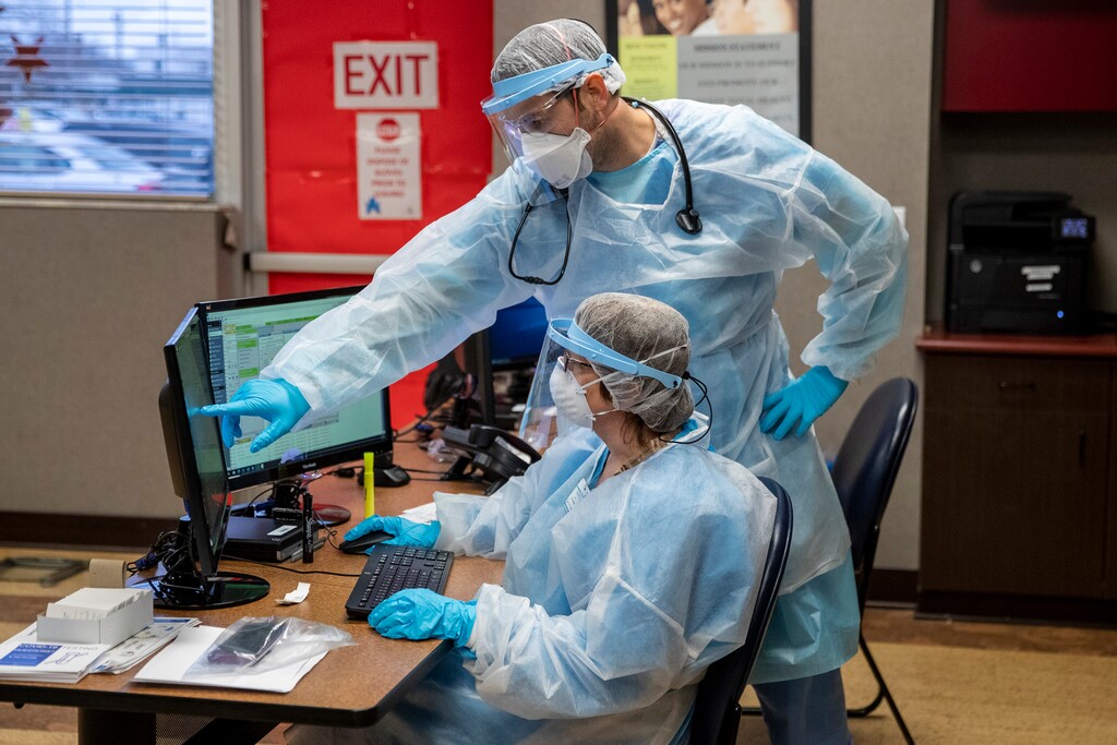FILE - In this Nov. 13, 2020, file photo, Physician assistant Steven Oginsky, top, and registered nurse Kim Alder work inside the Hackley Community Care COVID-19 triage room at 2700 Baker Street in Muskegon Heights, Mich. (Cory Morse/The Grand Rapids Press via AP, File)