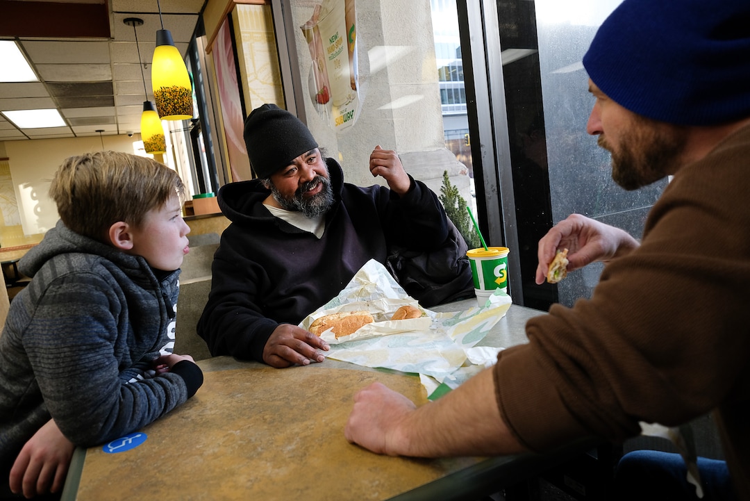 (Francisco Kjolseth  |  The Salt Lake Tribune) Viliami Taufalele, center, who has been homeless since 1999, gets a meal courtesy of 10-year-old Chase Hansen and his father John on Monday, Dec. 16, 2019. Chase who started an organization called Project Empathy at the age of 6, spends time with people experiencing homelessness in an effort to connect with people on a personal level.