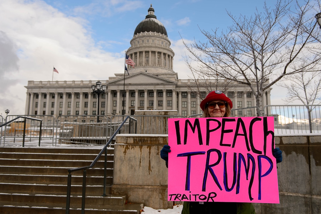 (Trent Nelson | The Salt Lake Tribune)  Kris Moore holds up a sign as protesters gather before a visit by President Donald Trump, Monday December 4, 2017.