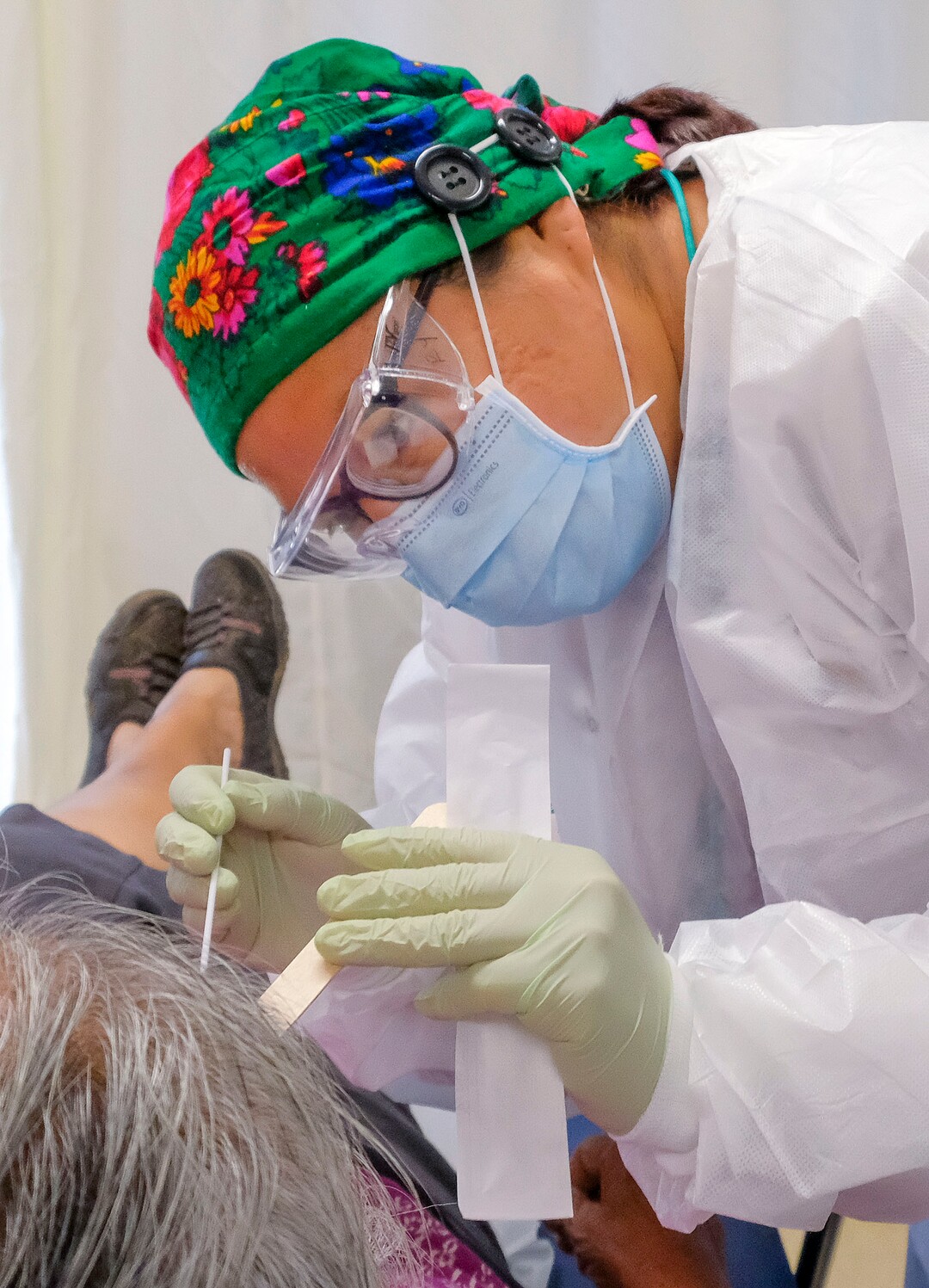 (Leah Hogsten  |  The Salt Lake Tribune) Navajo Mountain Health Clinic lab tech Roxanna Yazzie swabs the tonsils of a 74-year-old Diné patient believed to have had strep throat Aug., 25, 2020. The clinic currently serves dental patients one at a time and patients who need urgent medical care or coronavirus testing.