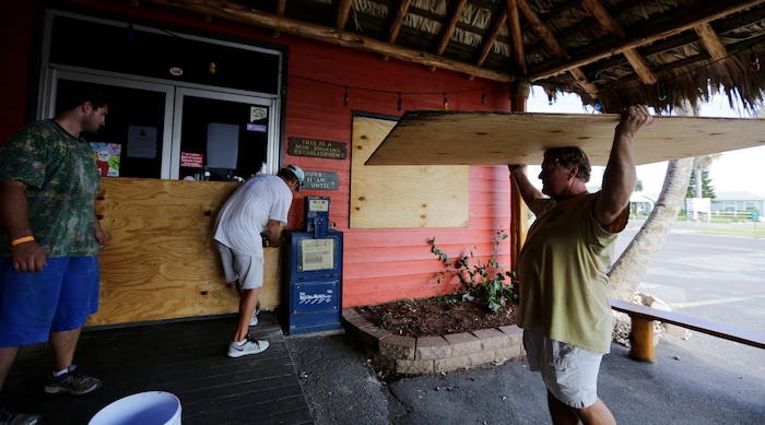 (Eric Gay | The Associated Press) Mac Owens, left, Mark Jones, center, and Kelly Owens, right, board up their business in preparation for Hurricane Harvey, Thursday, Aug. 24, 2017, in Port Aransas, Texas. Harvey intensified into a hurricane Thursday and steered for the Texas coast.