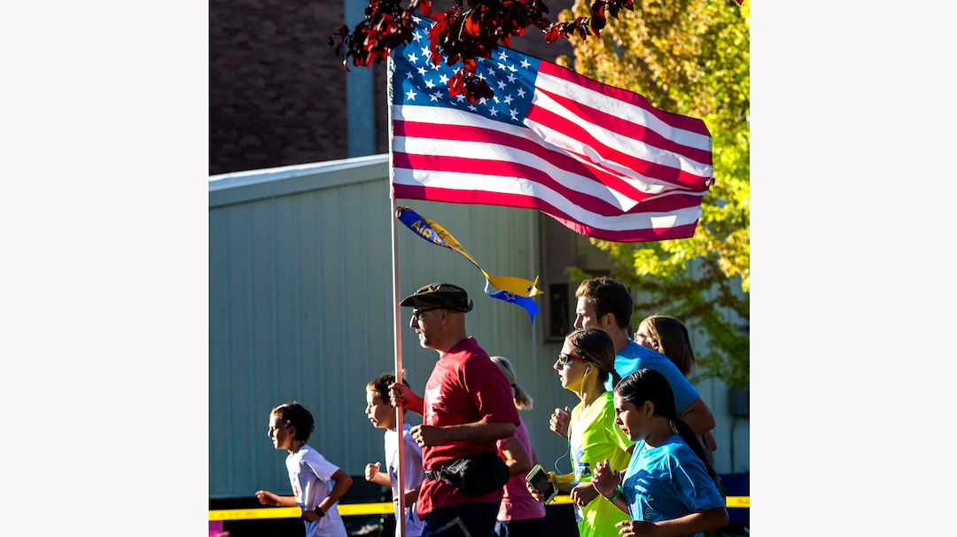 (Rick Egan | The Salt Lake Tribune) Paul Hubenthal carries the American Flag as he runs in the Layton Fun Run, during the Layton Liberty Days Celebration, on Monday, July 5, 2021.