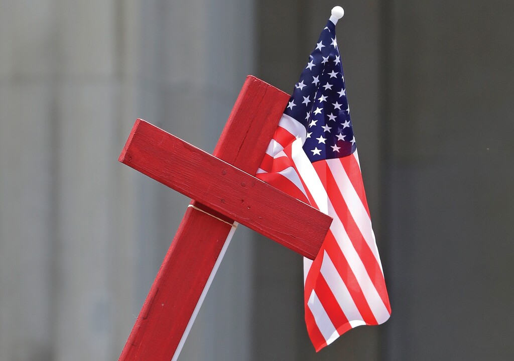 A protester holds a cross and the American flag during a rally outside the Theodore Levin United States Courthouse, on  June 21, 2017, in Detroit. (AP Photo/Carlos Osorio)