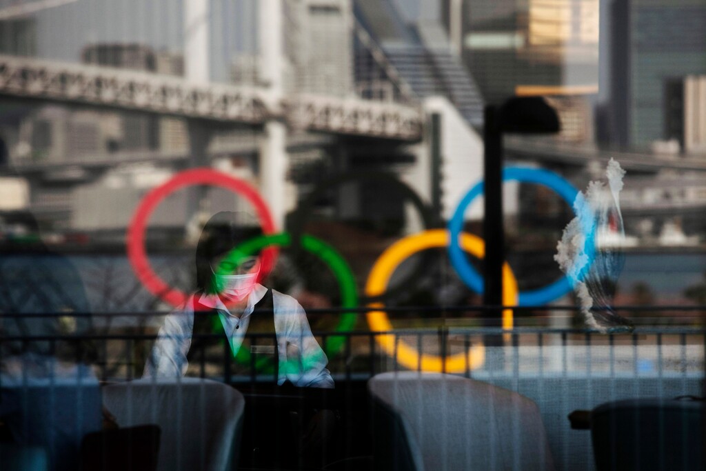 (Jae C. Hong | AP) The Olympic rings are reflected on the window of a hotel restaurant as a server with a mask sets up a table Monday, Feb. 24, 2020, in the Odaiba section of Tokyo.