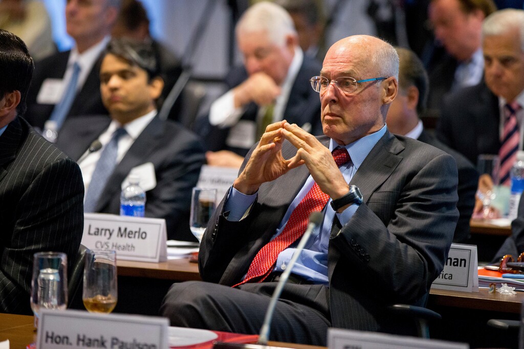 FILE - In this Sept. 16, 2015, file photo, former Treasury Secretary Henry Paulson listens as President Barack Obama speaks to business leaders at the quarterly meeting of the Business Roundtable in Washington to renew his calls for increased spending in infrastructure, education and scientific research. Three officials including Paulson who played vital roles in combating the 2008 financial crisis say they worry that the painful lessons from the banking system’s near-collapse a decade ago may be forgotten. (AP Photo/Andrew Harnik, File)