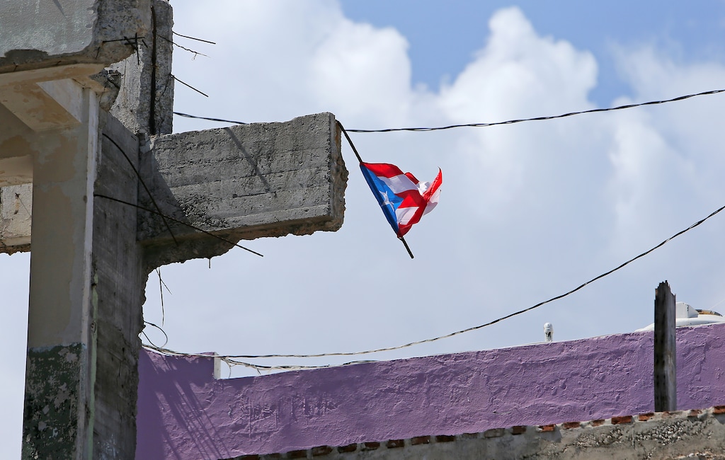 (David Santiago/Miami Herald via AP) In this Monday, Oct. 23, 2017, photo, a Puerto Rican flag flies over the ruins of a building damaged by Hurricane Maria in San Juan, Puerto Rico.