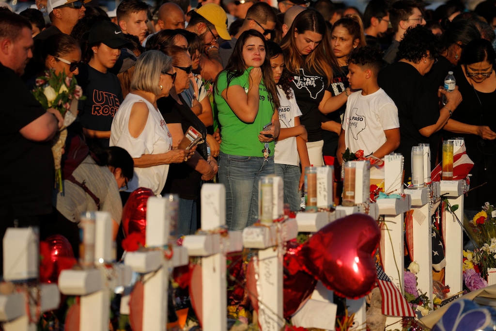 FILE - In this Aug. 6, 2019, file photo, people visit a makeshift memorial at the scene of a mass shooting at a shopping complex in El Paso, Texas. At the growing memorial for the victims of this Saturday massacre, the city’s roots in Catholicism and religion in general loom large. (AP Photo/John Locher, File)