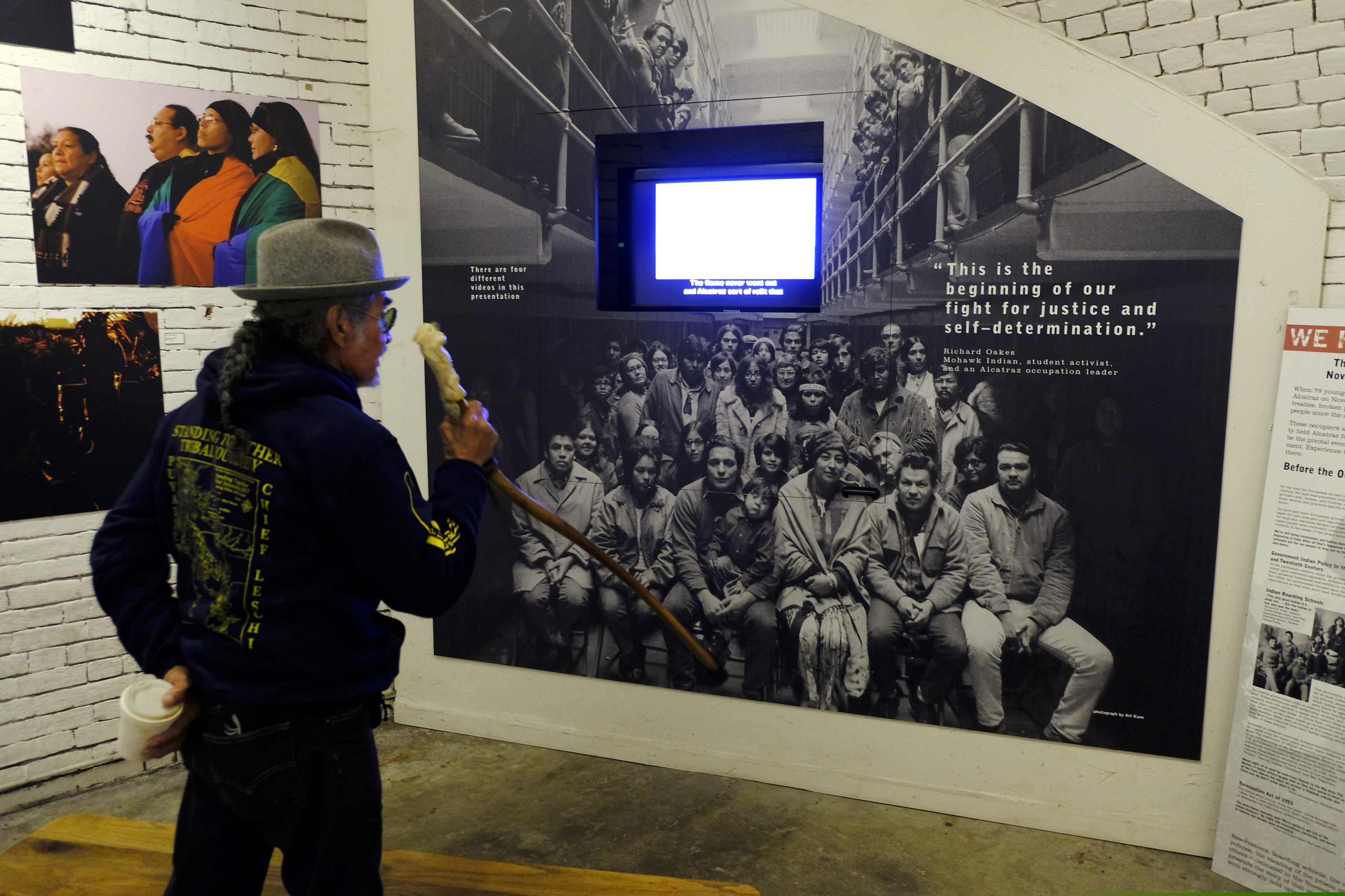 (Eric Risberg | AP) In this photo taken Tuesday, Nov. 12, 2019, Eloy Martinez, who took part in the Native American occupation of Alcatraz 50 years earlier, looks over a group photograph showing the occupiers displayed in an exhibit on the island in San Francisco. The week of Nov. 18, 2019, marks 50 years since the beginning of a months-long Native American occupation at Alcatraz Island in the San Francisco Bay. The demonstration by dozens of tribal members had lasting effects for tribes, raising awareness of life on and off reservations, galvanizing activists and spurring a shift in federal policy toward self-determination.