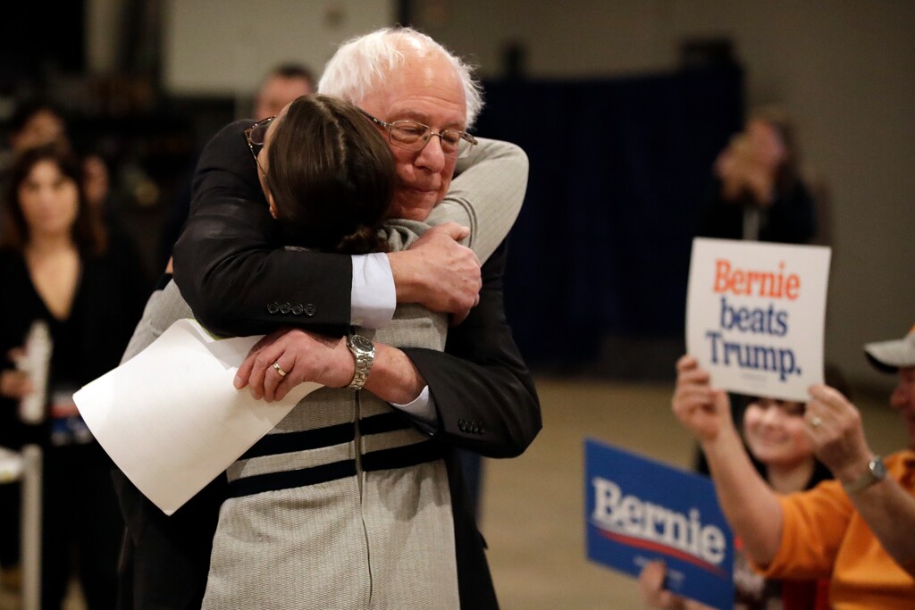 Democratic presidential candidate Sen. Bernie Sanders, I-Vt., center, hugs Rep. Alexandria Ocasio-Cortez, D-N.Y., after Sanders walked up to the podium to speak during a campaign event Saturday, Jan. 25, 2020, in Marshalltown, Iowa. (AP Photo/Marcio Jose Sanchez)